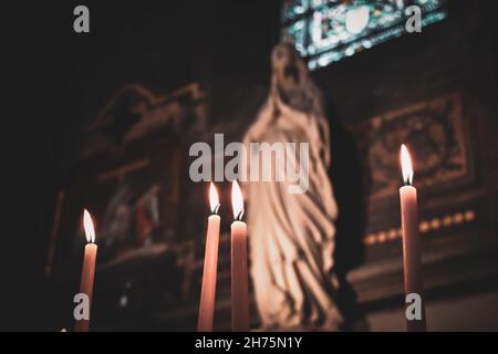 Candles lit in the church with the altar and christian icons in the background. Roman Catholic religion. Religious concept Stock Photo