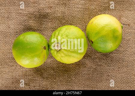 Three organic juicy bergamot on burlap, close-up, top view. Stock Photo