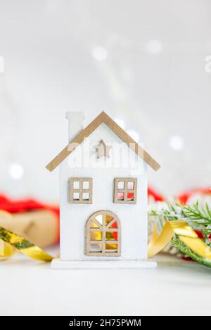 toy decoration house made of wood on white snow with branches of Christmas tree on holiday new year and christmas Stock Photo