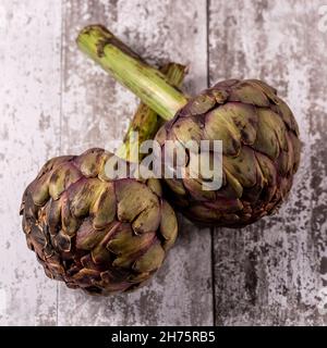 Looking down on globe artichokes on a table, with a shallow depth of field Stock Photo