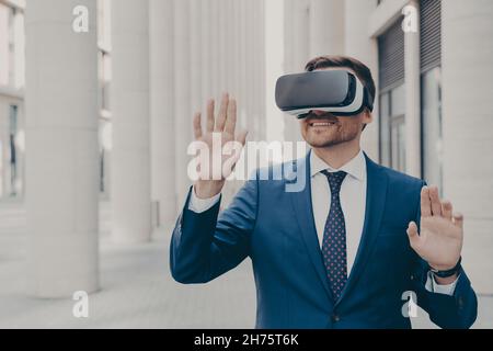 Professional male architect in augmented reality headset gesturing while standing outdoors Stock Photo