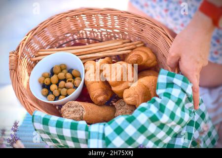 mini croissants in a picnic basket in nature. girl holding picnic basket with food Stock Photo
