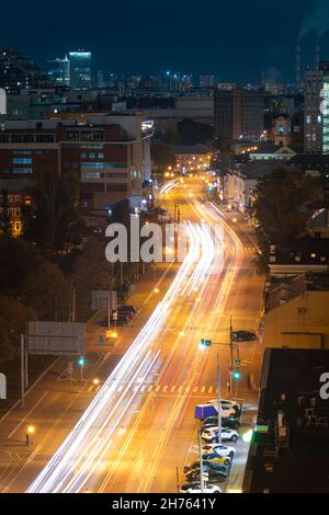 Aerial view of the wide street of the night city which cars move along and leave traces of light from the carlights Stock Photo