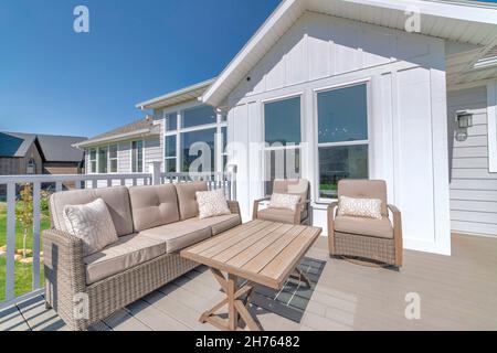 Patio of a house on a wooden deck with railings and woven furnitures Stock Photo