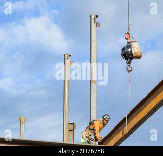 NEW ORLEANS, LA, USA - NOVEMBER 17, 2021: Construction worker receiving a steel beam from a crane and setting it in place on a new building Stock Photo