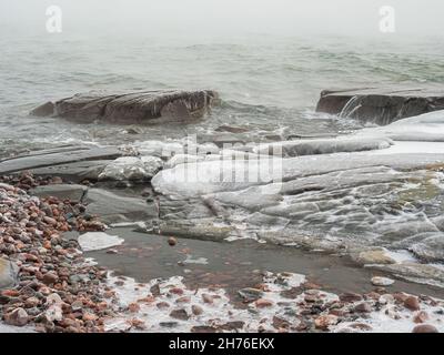 Ice covered rocks and freezing water along the shore of Lake Superior in winter Stock Photo