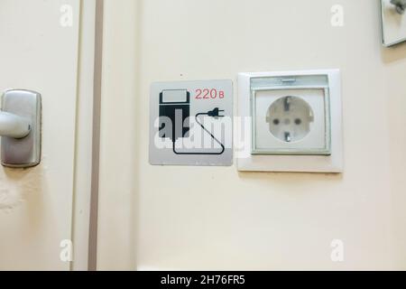 Electricity outlet (220 V) with a picture of the shaving razor in the bathroom wc of the train Couchette carriage, Kazakhstan railway Stock Photo