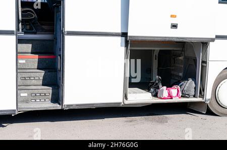 Open luggage cabin and side stairs of the lower part of Mercedes-Benz bus standing with doors open. Stock Photo