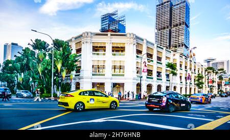 Taxis travelling along Bras Basah Road, passing by Raffles Hotel, Singapore. Stock Photo