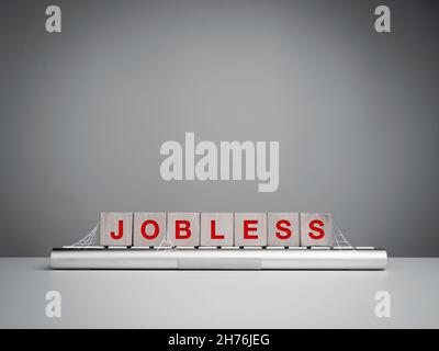 Jobless, unemployment concept. The red words "jobless" on wooden blocks on abandoned keyboard computer with cobwebs on white table on grey background Stock Photo