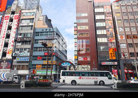 The Kabukicho district in Shinjuku City, Tokyo, Japan with traffic and buses on the road. Stock Photo