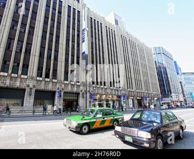 The Isetan Shinjuku flagship store located in Shinjuku, Tokyo, Japan with taxis and other vehicles driving past at a busy intersection. Stock Photo