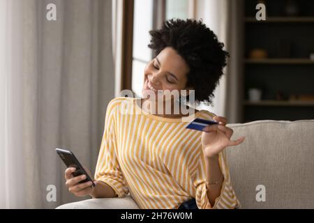 Happy young African consumer woman excited with shopping on internet Stock Photo