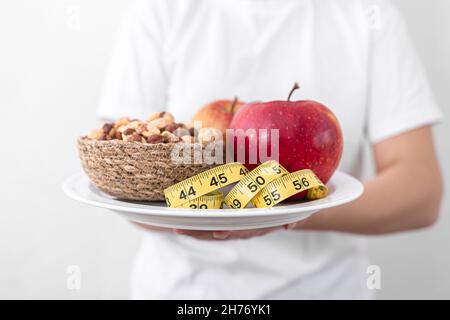 Plate with apples, nuts and measuring tape, diet and healthy food concept. Stock Photo
