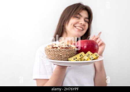 A plate with apples, nuts and a measuring tape in the hands of a young woman. Stock Photo