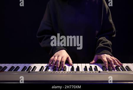 Female hands play piano keys in a dark, hazy room. Stock Photo