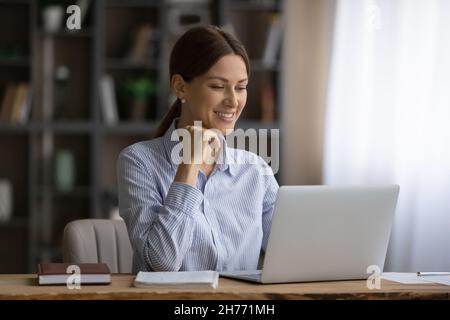 Attractive smiling business lady sit at workplace working on laptop Stock Photo