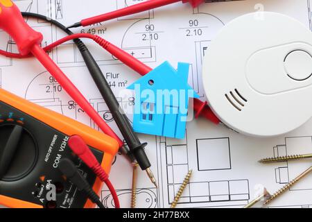 smoke detector with a screwdriver and a measuring device on a circuit diagram Stock Photo