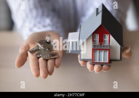 Close up young woman holding keys and house model. Stock Photo