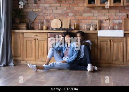 Joyful young African American family couple sitting on floor. Stock Photo