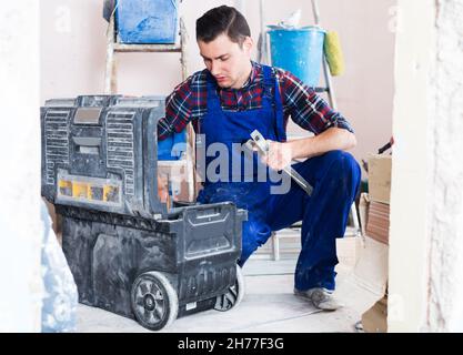 Worker looking for necessary tool in toolbox Stock Photo