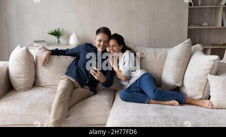Couple relaxing indoor having fun watch funny videos on cellphone Stock Photo