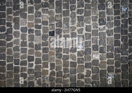 Overhead shot of a cobblestone structure on the ground of an urban street in gray and textured tones. Background concept. Stock Photo