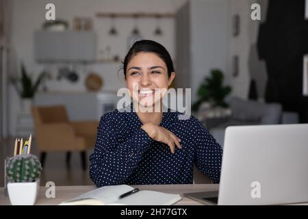 Smiling dreamy young Indian woman looking in distance. Stock Photo
