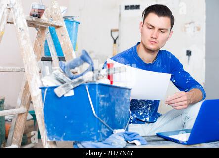 Male contractor working with papers and laptop Stock Photo