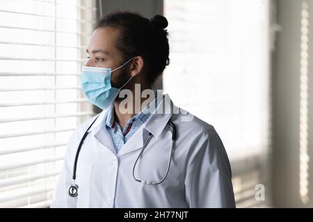 Profile pensive African American man doctor in medical mask thinking Stock Photo