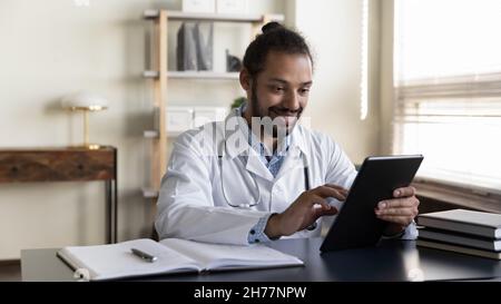 Smiling African American man doctor using tablet in office Stock Photo