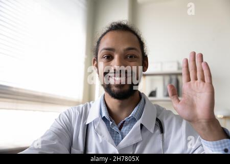 Head shot portrait smiling African American man doctor waving hand Stock Photo