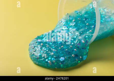 blue slime with glitter flows from plastic container Stock Photo