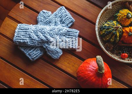 Knitted fingerless glove on wooden table. Autumn decoration with pumpkins Stock Photo