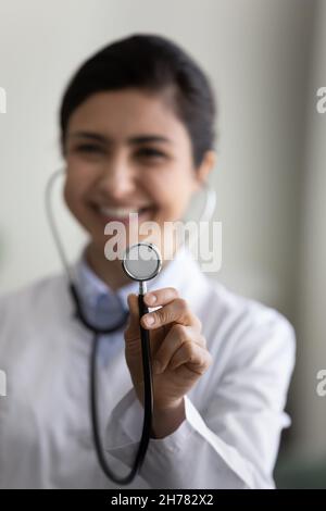 Vertical photo close up smiling Indian female doctor holding stethoscope Stock Photo
