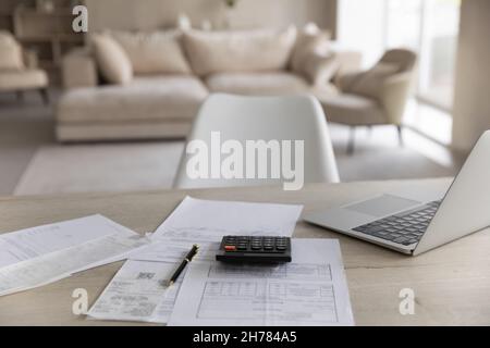 Empty wooden work desk with calculator, laptop and financial documents Stock Photo