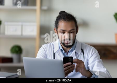 Confident African American man doctor using smartphone in office Stock Photo