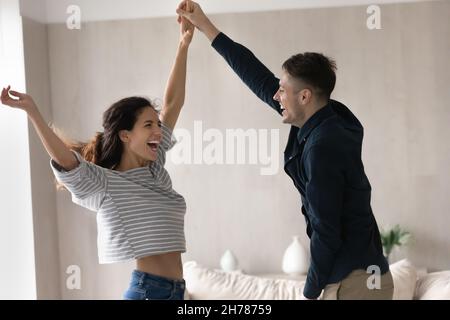 Cheery couple holding hands dancing at home Stock Photo
