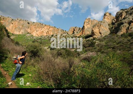 Israel, Galilee, Amud (Pillar) stream nature reserve and park A female hiker admires the view from the trail Stock Photo
