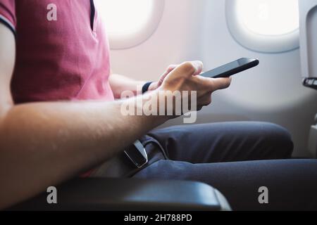 Hands holding smart phone in airplane. Passenger using internet connection during flight. Stock Photo