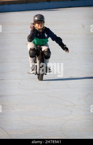 A young pre-teenage girl fearlessly rides on an Imotion electric unicycle in Flushing Meadows Corona Par in queens, New York City. Stock Photo