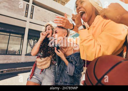 Friends laughing together outdoors. Group of generation z friends having fun while walking together in the summer sun. Cheerful young having a good ti Stock Photo