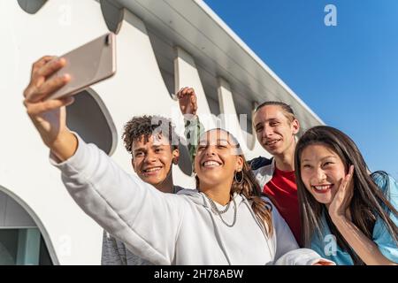 Group of happy teenage friends taking a selfie and laughing in the city street. Stock Photo