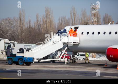Passenger plane at airport in winter. Landing passengers in airliner in winter. Modern twin-engine passenger airplane at airport during Stock Photo