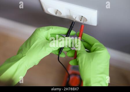 Measuring voltage with a multimeter, hands in rubber gloves Stock Photo