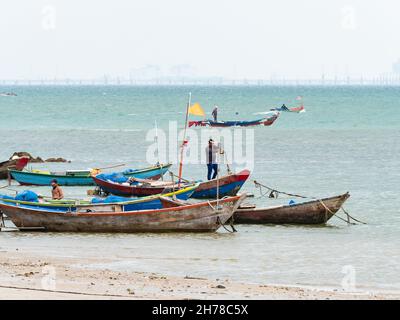 Small fishing boats moored at Pala Beach, Ban Chang in the Rayong province of Thailand. Oil pipeline at Map Ta Phut Industrial Estate can be seen over Stock Photo