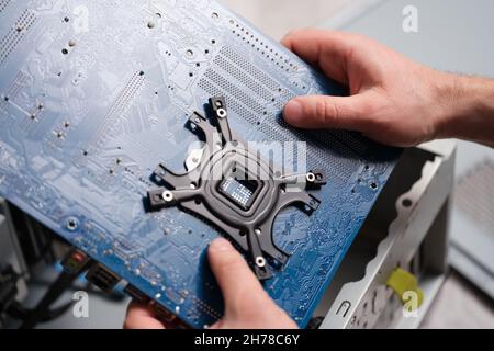 A man holds a motherboard over a pc, close-up Stock Photo