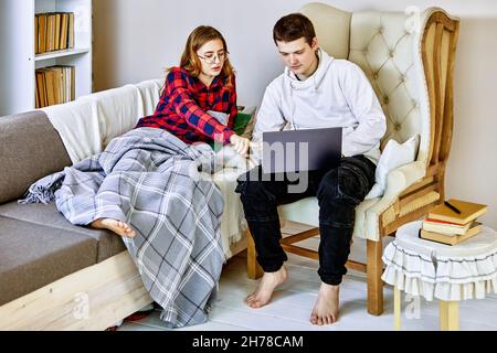 Setting up your computer to teleworking, friend helps young woman prepare laptop to work from home. Stock Photo
