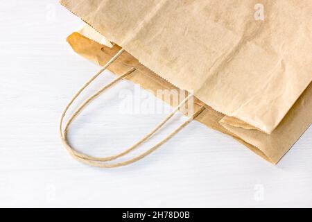 Beige craft paper bag on light wooden table with copy space. Eco-friendly zero waste recycling and disposable package for market purchases and home de Stock Photo