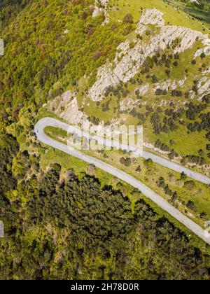 Aerial view of the sharp turn of the serpentine road in the mountains and forest. Stock Photo